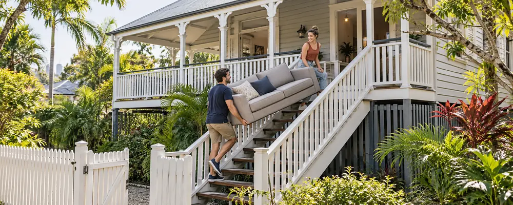 Couple moving a sofa upstairs, illustrating IT migration during a business merger.